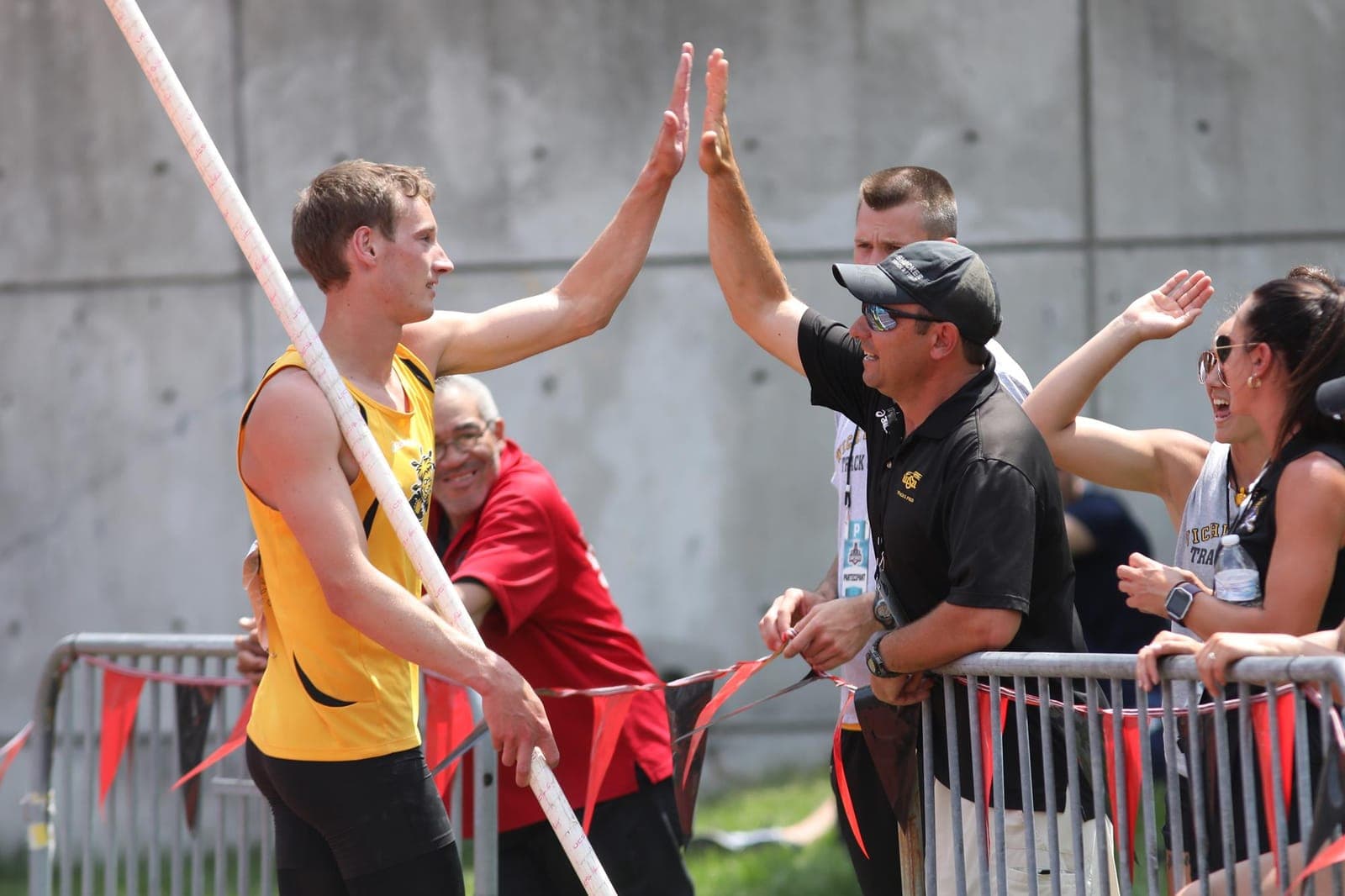Coach high-fiving a young vaulter